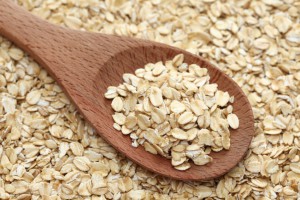 Rolled oats (oat flakes) in a wooden spoon on a rolled oats background. Close-up.